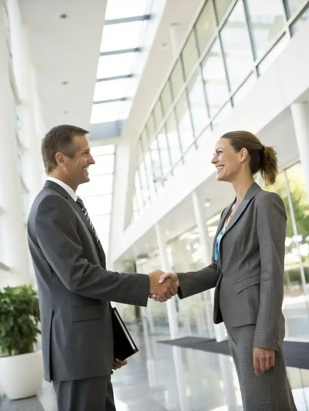 A person in a business suit shaking hands with another person, representing employment screening and background checks.